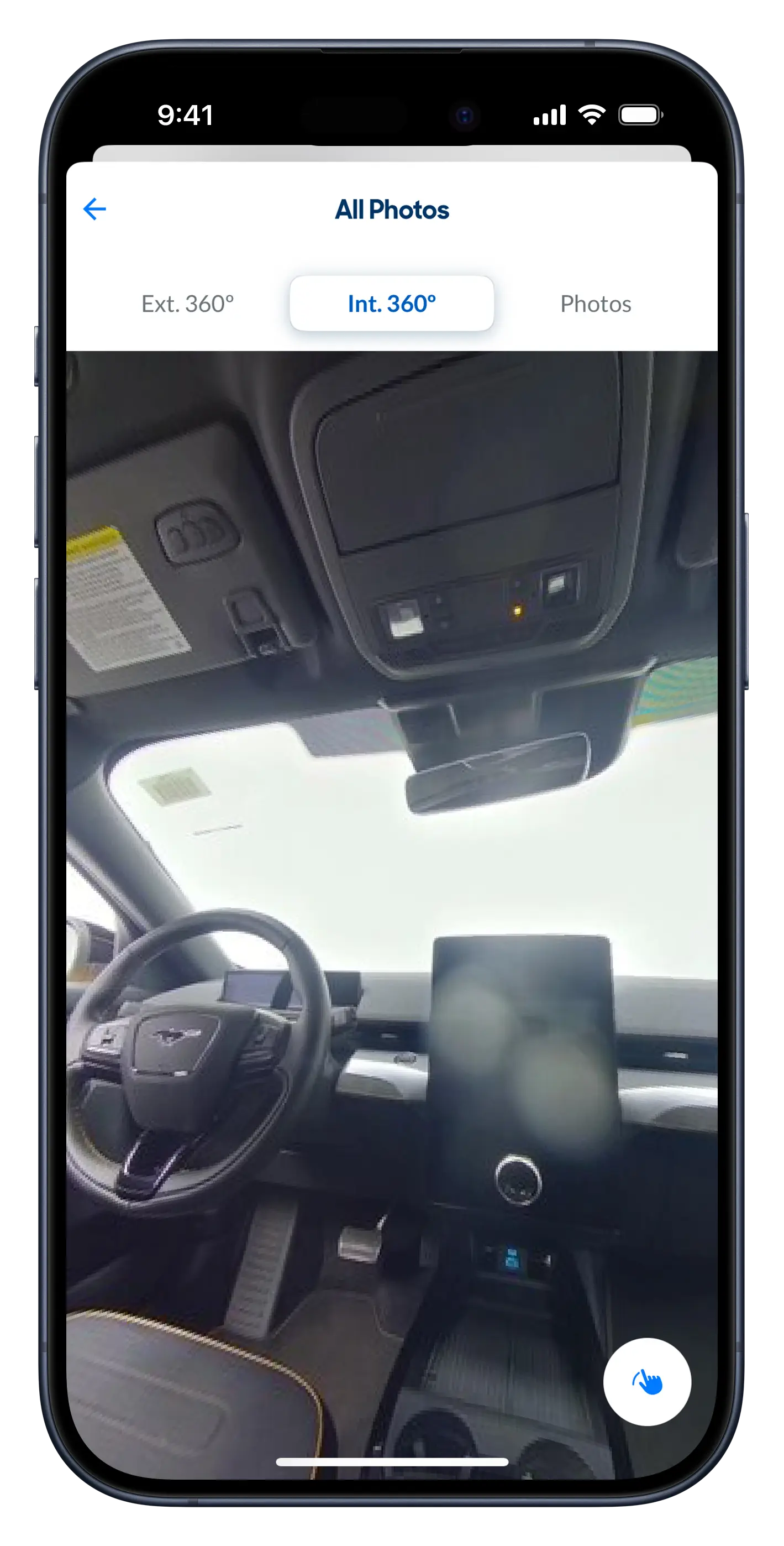 Screenshot of the CarMax app vehicle detail screen, displaying the inside of a Ford Mustang Mach-E. A button is displayed in the lower right corner that shows a finger making an arc.